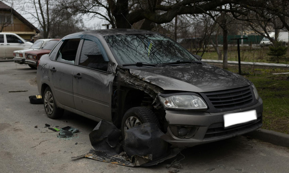 A damaged car after an accident, on the side of the road.