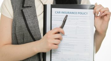 Woman holding a car insurance policy form.