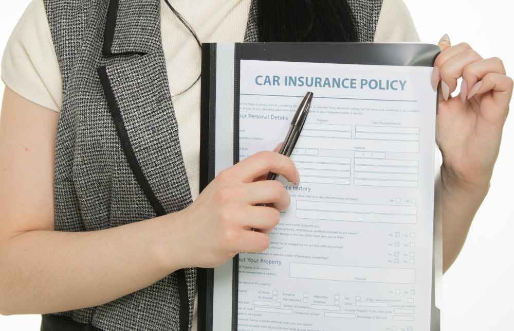 Woman holding a car insurance policy form.